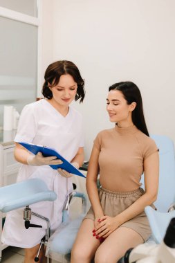 Jinekolog, Pap test sonuçlarını hastasıyla tartışıyor. Jinekolog, bir klinikte hastasıyla birlikte teşhis bulgularını inceliyor.