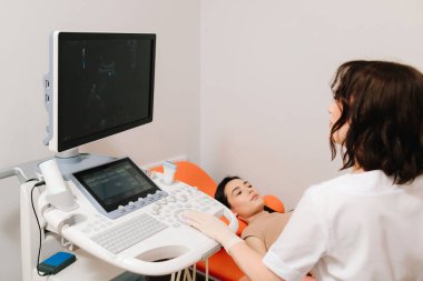 Jinekolog üreme sağlığı değerlendirmesi için ultrason cihazı kullanıyor. Jinekolog, sakin bir hastaya karın ultrasonu uygular. Karın ultrasonu.