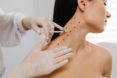 Kozmetik uzmanı kızın platizmasına botulinyum toksin enjekte etmeden önce nokta çiziyor. Nefertiti boyunda işaretli noktalarla enjeksiyonu kaldırıyor.