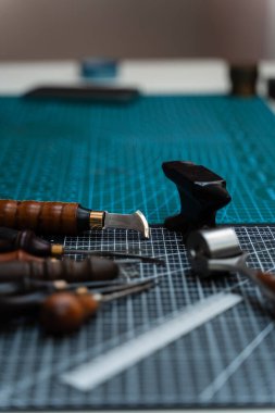 Traditional wooden-handled awls and cutters beside a small anvil illustrate timeless craftsmanship and dedication to bespoke design. Leathercraft Tools on Workbench
