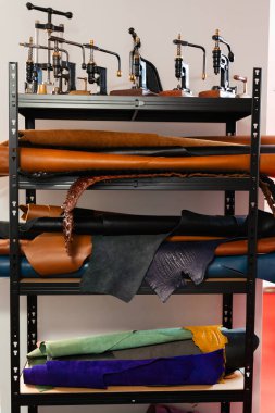 Leather rolls and classic vintage presses fill the craftsman workshop shelves. Retro leathercraft presses and shelves of cowhide hides create a true artisan studio