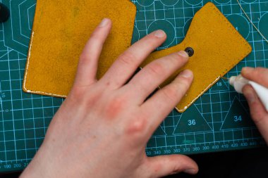 Deri ustaları dikiş atmadan önce kenar hazırlamak için yapıştırıcı kullanır. Deri kenarlara yapıştırıcı sürüyorum. Deri ürünler üretimi güçlü yapıştırıcıları güvenli bir şekilde yapıştırmakla başlar.