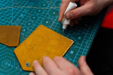 Deri ustaları dikiş atmadan önce kenar hazırlamak için yapıştırıcı kullanır. Deri kenarlara yapıştırıcı sürüyorum. Deri ürünler üretimi güçlü yapıştırıcıları güvenli bir şekilde yapıştırmakla başlar.