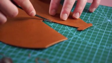 Alet 4K video ile deri kenar buduyorum. Zanaatkar, deri kenarları hassas aletlerle keser ve kesiği rafine eder. Sanatçı, pürüzsüz kıvrımlar ve temiz hatlar sağlayan, budama aracı ile deri kenarları rafine eder.