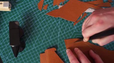 4K numaralı bıçakla deri kesme videosu. Zanaatkar deriyi dikkatli bir şekilde hassas aletlerle keser. Sanatçı, deri parçaları hassas bir şekilde keserek, doğru şablonları sağlayarak hazırlar..