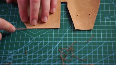 Esnaf, deri kenarları hassas aletlerle süsler ve 4K 'lık kesim videosunu rafine eder. Zanaatkar deri kenarları budama aletiyle rafine eder, pürüzsüz kıvrımlar ve temiz hatlar sağlar. Deri kenarı aletle buduyor.