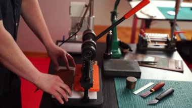 Zanaatkar, deri 4K videoya desenler yüklemek için basın makinesi kullanıyor. Deri baskı el yapımı tasarımlara güç ve detay sağlar, cüzdanlar, kemerler ve aksesuarlar için prim sonuçları yaratır..