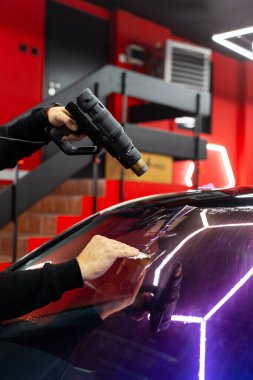 Isı tabancası ve plastik cam macunuyla mor bukalemun filmi kullanarak baloncukları temizler ve mükemmel bir yapışkanlık sağlar. Ön cam ya da ön far. Mor bukalemun. Isı tabancası ve cam sileceği ile yumuşatılıyor.