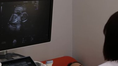 Hastanenin 4K videosunda ultrasonda hamile bir kadın var. Ultrason cihazıyla hamilelik sağlık kontrolü.