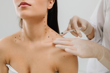 Nefertiti boynundaki işaretli noktalarla enjeksiyonu kaldırıyor. Kozmetik uzmanı kızın platizmasına botulinyum toksini enjekte edilmeden önce nokta çiziyor.