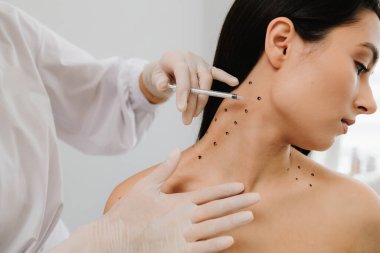 Nefertiti boynundaki işaretli noktalarla enjeksiyonu kaldırıyor. Kozmetik uzmanı kızın platizmasına botulinyum toksini enjekte edilmeden önce nokta çiziyor.