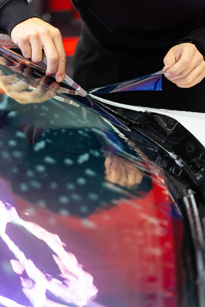 Обрезка фиолетового цвета хамелеона на лобовом стекле автомобиля с точным ножом, создавая гладкие, без пузырей края. Тонировка лобового стекла фиолетовая хамелеонная пленка на лобовом стекле автомобиля в деталях