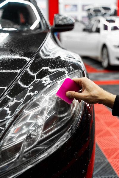 Инсталляция защитной пленки фар использует сглаживающее устройство для сглаживания пленки и удаления пузырьков воздуха для безупречной отделки. Дистрибьютор использует прижимный инструмент для сглаживания защитной пленки фар