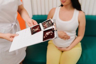 Jinekolog randevusu sırasında hastaya yüksek hemoglobin ve kan basıncı hakkında danışmanlık yapmak. Jinekolog, hamile bir kadının kan testinin sonuçlarını tartışıyor.