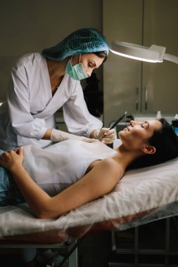 Cildiyeciler radyoaktif gerilim ameliyatı kullanarak kesin bir radyo dalgası temizliği yapıyorlar. Radyo dalgası dermatolojik mol kesimine yakın çekim. Klinik koşullar altında radyoaktivite köstebeği temizleme