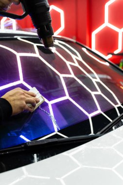 Isı tabancası ve plastik cam macunuyla mor bukalemun filmi kullanarak baloncukları temizler ve mükemmel bir yapışkanlık sağlar. Ön cam ya da ön far. Mor bukalemun. Isı tabancası ve cam sileceği ile yumuşatılıyor.