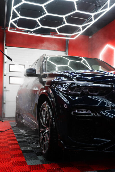 Car detailing process with high pressure water rinses dirt and foam from body panels and headlights leaving paint and glass spotless. High pressure water jet to remove dirt and foam from car body