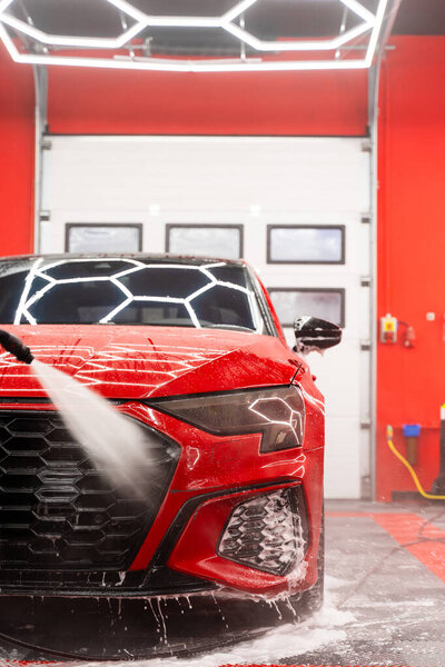 Snow foam car wash coats the vehicle in a milk-like layer, safely lifting dirt and road grime before detailing. Milky pre-wash foam in auto detailing loosens contaminants from paint