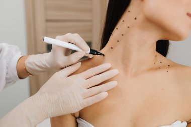 Kozmetik uzmanı bir kadının platizmasına botulinyum toksin enjekte edilmeden önce nokta çiziyor. Bir profesyonelden boyun geliştirme. Kadın estetik kozmetolojisi. Nefertiti kaldırmadan önce işaretle