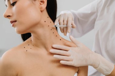 Nefertiti boynundaki işaretli noktalarla enjeksiyonu kaldırıyor. Kozmetik uzmanı kızın platizmasına botulinyum toksini enjekte edilmeden önce nokta çiziyor.