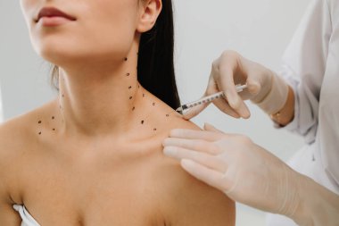 Nefertiti boynundaki işaretli noktalarla enjeksiyonu kaldırıyor. Kozmetik uzmanı kızın platizmasına botulinyum toksini enjekte edilmeden önce nokta çiziyor.