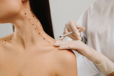 Kozmetik uzmanı kızın platizmasına botulinyum toksin enjekte etmeden önce nokta çiziyor. Nefertiti boyunda işaretli noktalarla enjeksiyonu kaldırıyor.