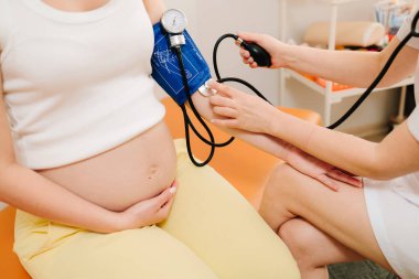 Hamilelik sırasında yüksek basınç sorunu. Jinekolog, doğum merkezinde hamile bir hasta için kan basıncını ölçer.