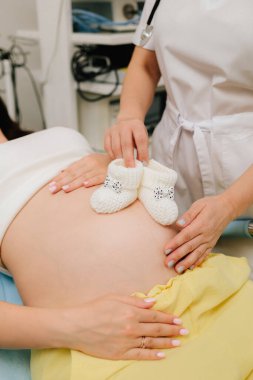 Bebeğini beklerken küçük bebek popolu bir anne bekliyor. Karnında bebek paçası olan hamile bir kadın ve jinekolog.