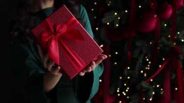 Elinde Noel hediyesi olan bir kız. Yeni yıl ağacı 4K videosunun hemen yanında..