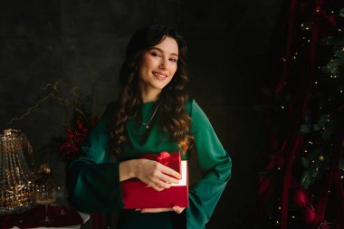 Kadın, yeni yıl ağacının yanında parlayan kırmızı Noel hediyesini sihirli ışıkla açıyor.