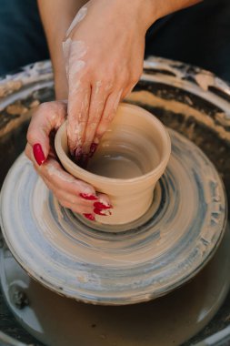 Kız, çömlek çarkındaki killeri gülümseyerek şekillendiriyor. Gülümseyen esnaf, dönen çömlek çarkının üzerindeki çamuru şekillendirir. Çömlek çarkında kille çalışırken gülümseyen genç bir kadın.