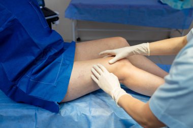 Doktor vasküler değerlendirme için bacak damarlarını muayene ediyor ve muayene ediyor.