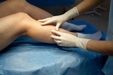 Doktor görsel ve manüel teknikler kullanarak vasküler bacak muayenesi yapıyor.