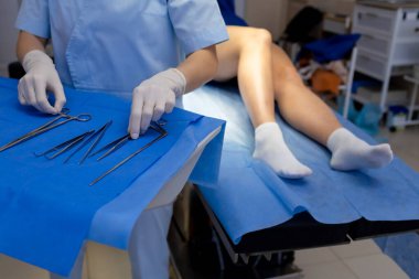 Doktor bacak damar prosedürü için cerrahi aletler kuruyor