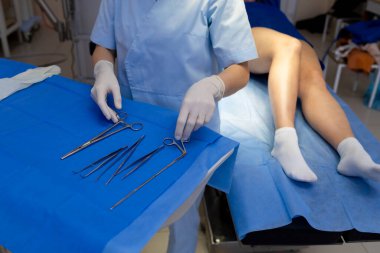 Sağlık uzmanı bacak damarı ameliyatı için cerrahi aletler hazırlıyor.