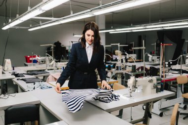 Tasarımcı dikiş dikmeden önce kumaşı masanın üzerine yayar