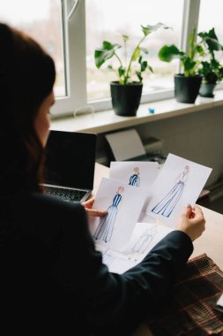 Tasarımcı giysileri kağıda çizer, desenleri ve tasarımları düzenler
