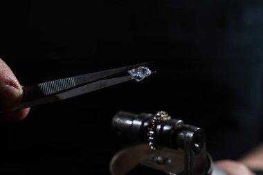 Büyük elmas yüzük üzerinde kuyumcu tarafından inceleniyor.