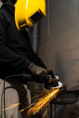 Çalışanlar endüstriyel ortamda çeliği keserken açılı değirmen kıvılcımları uçuşuyor