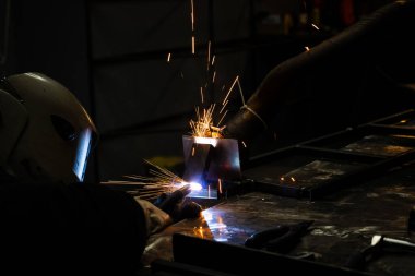 Flux çekirdekli elektrot SMAW koruyucu kasklı işçiler tarafından kaynaklanıyor.