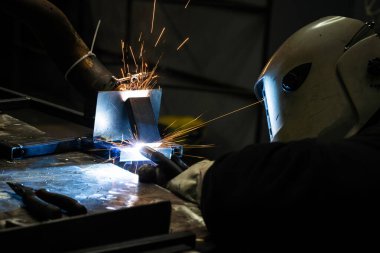 Endüstriyel çelik kaynaklama SMAW süreci ve kıvılcımlar uçuşuyor