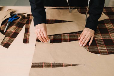 Tasarımcı kumaş üzerine tebeşir ve giysi desenleri çiziyor.