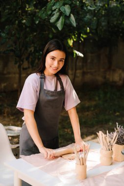 Masanın üzerinde yuvarlanan bir çivi düzleştirici kil var. Clay, seramik sanat sahnesini hazırlamak için çok hassas bir şekilde yuvarlandı. Çamur, çanak çömlek ve seramik sanat malzemelerini şekillendirir.