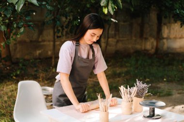 Kil, geleneksel çömlekçiliği tanımlayan sanat ve zanaatkarlıktan zevk almak için hazırlanıyor. Önlüklü genç bir kadın dışarıdaki çömlek atölyesinde kil serpiştiriyor.