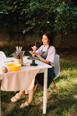 Esnaf, üzerinde ayrıntılı çizgiler olan bir kil yaprak oyar. Clay Leaf 'i oyan kadın. Genç bir kadın çömlekçilik yeteneklerini sergilemek için kilden ince yaprak desenleri oyuyor.