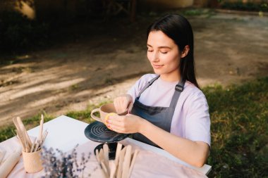 Clay Bowl 'u şekillendiren genç kadın. Potter, tekerleğinde sünger olan, şekil ve dokuları rafine eden bir kir kabını yumuşatır. Sanatçı kilden bir kase üzerinde dikkatle çalışır, şeklini süngerle düzeltir.