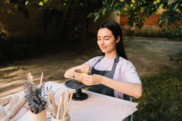 Clay Bowl 'u şekillendiren genç kadın. Potter, tekerleğinde sünger olan, şekil ve dokuları rafine eden bir kir kabını yumuşatır. Sanatçı kilden bir kase üzerinde dikkatle çalışır, şeklini süngerle düzeltir.