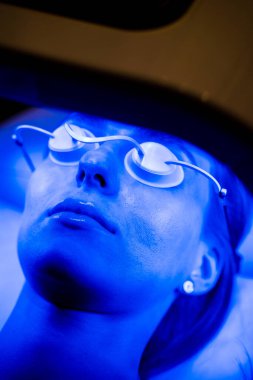 Kozmetik uzmanı hastalara LED kubbe yüz tedavisi uyguluyor.