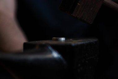 Kuyumcu metal halkayı şekillendirmek için çekiç ve örs kullanıyor.