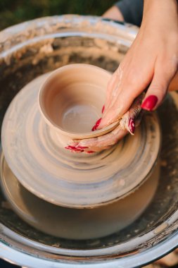 Çömlek tekerindeki kille çalışırken gülümseyen genç bir kadın. Kız, çömlek çarkındaki killeri gülümseyerek şekillendiriyor. Gülümseyen esnaf, dönen çömlek çarkında kil şekillendirir.